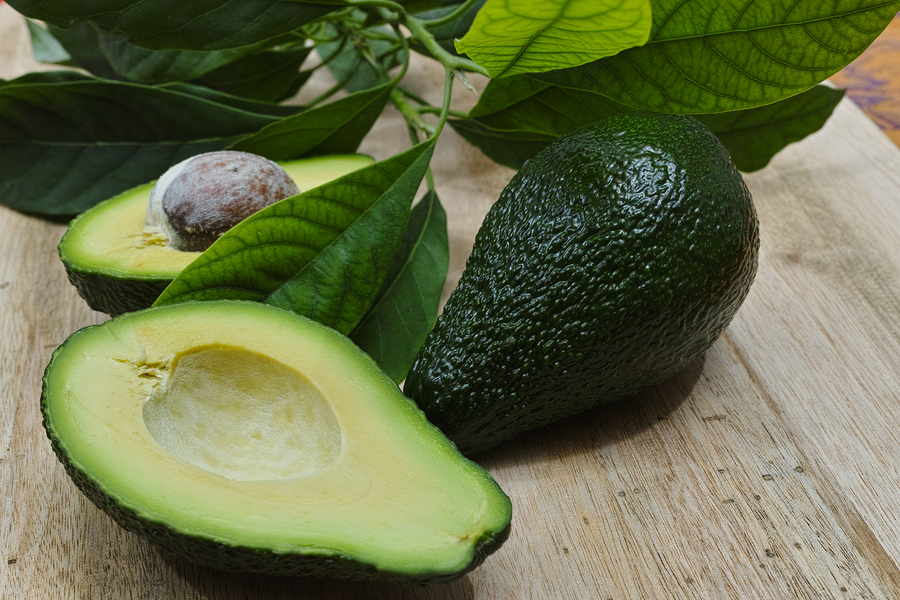 Fresh avocado with avocado leaves on teak wood table top